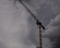 Construction crane rising against a backdrop of gray clouds