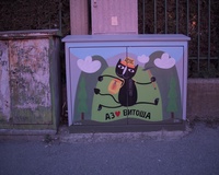 A street electrical box decorated with a picture of a humanoid cat with a backpack, with a forest-like background