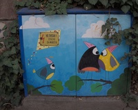 A street electrical box decorated with a picture of three birds composed from various geometric colorful shapes