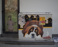 A street electrical box decorated with a picture of a large Saint Bernard dog on a city-like background