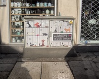 A street electrical box decorated with a picture of domestic animals in cages